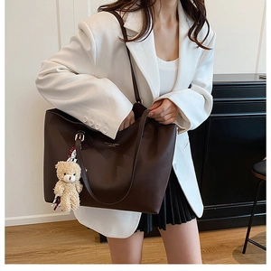 Détail du grand cabas en cuir marron foncé avec lettrage doré et charme d'ours peluche