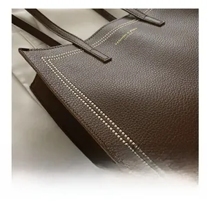 Gros plan des coutures blanches contrastées sur le sac cabas en cuir marron foncé