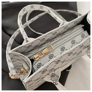 Close-up of canvas tote bag with black logo print, golden zipper and metal hardware