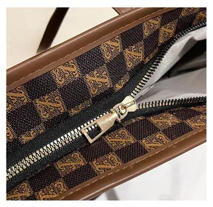 Detail of the golden zipper hardware and brown monogram pattern on the tote bag