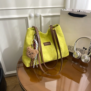 Large lime green tote bag with grid texture, brown handles, and a cute plush bear charm