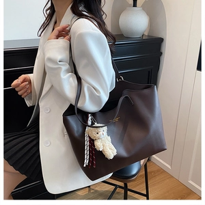 Détail d'un grand sac cabas en cuir marron foncé avec lettrage doré et pendentif