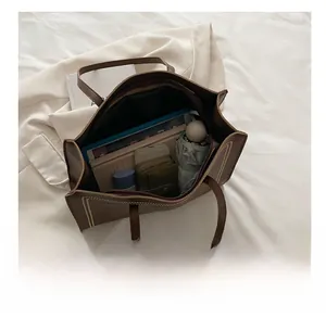 Vue de dessus montrant la grande capacité intérieure du sac cabas marron avec objets du quotidien
