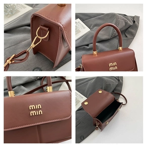 Close-up of brown PU leather bag with gold logo, adjustable strap and magnetic closure