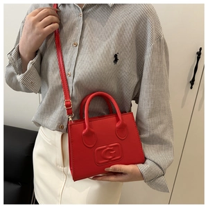Detail of red crossbody bag with embossed G logo and gold hardware on female model