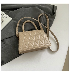 Détail d'un sac à main beige en similicuir matelassé avec surpiqûres triangulaires et métal doré