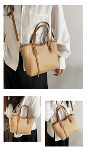 Detail of a minimalist beige leather tote with contrasting brown straps and metal hardware