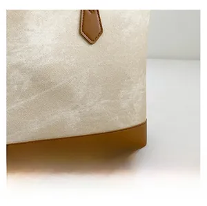 Detail of cream textured fabric tote bag with brown leather trim and neat stitching