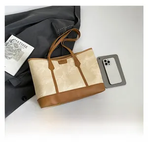 Close-up of a canvas and leather tote bag styled with a grey suit and accessories