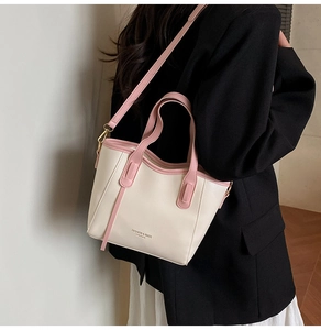 Close-up of cream leather bucket bag with pink contrast trim and adjustable strap