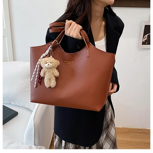 Vue détaillée d'un sac cabas marron en similicuir avec ours en peluche et breloque