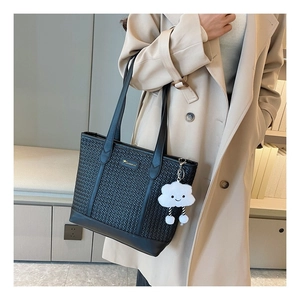 Détail d'un sac cabas noir tressé avec logo kangourou doré et charm en forme de nuage