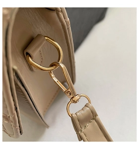 Macro shot of apricot leather bag showing golden lobster clasp and precise stitching details