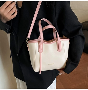 Detail view of the French bucket bag in cream PU leather on a model wearing a black blazer