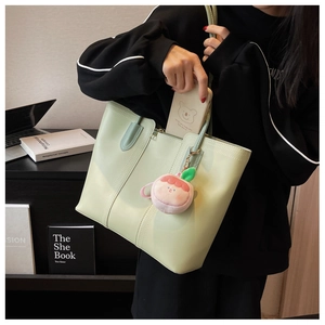 Close-up of light green tote bag showing smooth faux leather texture and large capacity