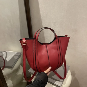 Deep red leather tulip bucket bag with black edge trim and adjustable gold hardware