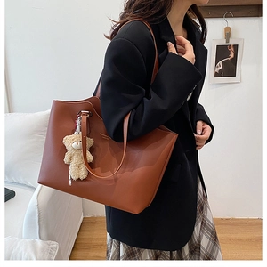 Vue détaillée du sac cabas en cuir marron avec un joli charm d'ours en peluche crème