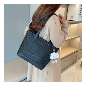 Détail d'un sac cabas noir tressé avec finitions en cuir et charme nuage en peluche