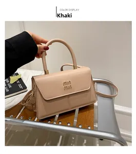 Detail of khaki faux leather square bag with gold min min logo and top handle