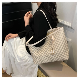 Detailed view of tote bag featuring repetitive M monogram print and metallic charm