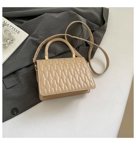 Detailed view of beige quilted PU leather shoulder bag with gold metal clasp and strap