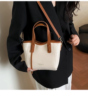 Detail of a chic cream leather bucket bag with brown handles on a black blazer outfit