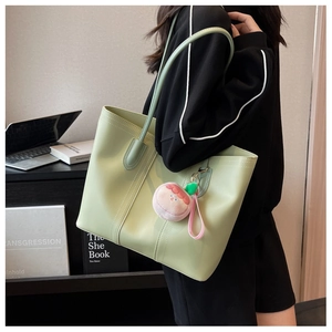 Detail of mint green tote bag featuring decorative stitching and a pink plush charm