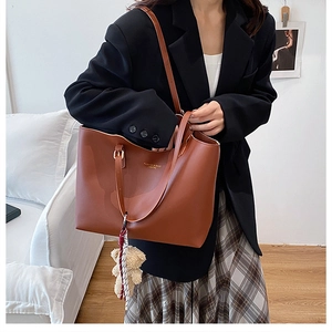 Grand sac cabas marron en similicuir avec porte-clé ours porté par un mannequin en tenue chic