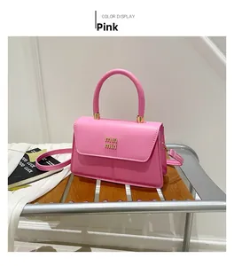 Close-up of pink faux leather handbag with min min gold logo and adjustable shoulder strap