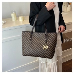Detail of monogram M print tote bag with golden letter charm and brown leather handle