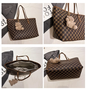 Detail view of brown checkered tote bag with gold metal hardware and plush bear charm