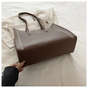 Détail du cabas en cuir marron à texture litchi avec lettrage doré et surpiqûres