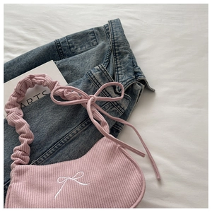 Detailed shot of pink corduroy shoulder bag with white bow embroidery and scrunchie strap