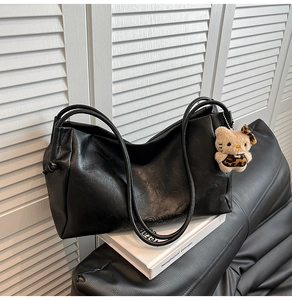 Close-up of black leather tote bag featuring RICHAD embossing and a cute leopard plush charm