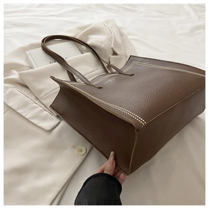 Détail du sac cabas en cuir grainé marron avec surpiqûres blanches et logo doré chic