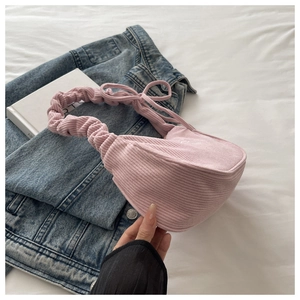 Detail of pink corduroy handbag featuring a scrunchie strap and bow tie accents
