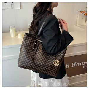 Brown monogram tote bag with gold M pendant shown on model in a modern interior
