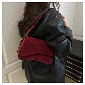 Detail of burgundy suede shoulder bag showing smooth matte texture and leather strap