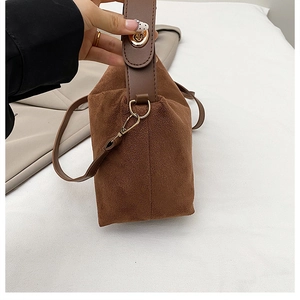 Detail der braunen Wildledertasche mit goldenem Drehverschluss und Lederriemen