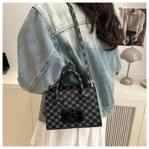 Woman in denim jacket carrying a black crossbody bag with geometric pattern and G logo