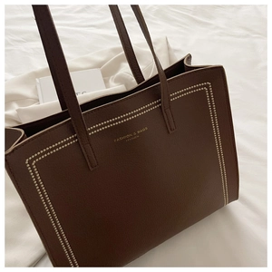 Détail du sac cabas en cuir grainé marron foncé avec lettrage doré et coutures blanches