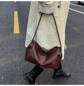 Close-up of textured leather shoulder bag with side knot detail and debossed logo