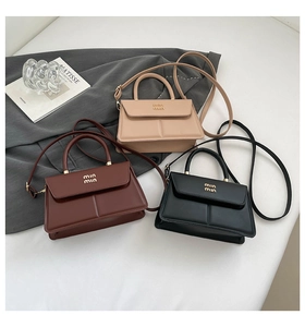 Detailed view of leather crossbody bags in beige, brown, and black with metal logo accents