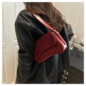 Detail of burgundy matte leather saddle bag with gold ring buckle and shoulder strap