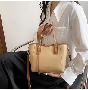 Detail of light beige paneled bucket bag with gold logo and detachable shoulder strap