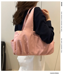 Detail of light pink nylon tote bag showing side pocket and pleated bottom texture