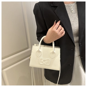 Detail of white PU leather crossbody bag with embossed G logo and elegant top handle