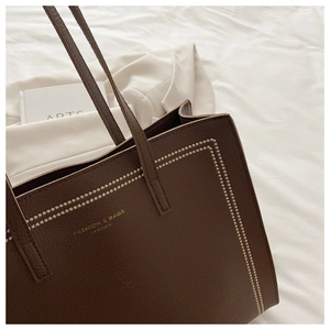 Détail du sac cabas marron foncé avec surpiqûres blanches et lettrage doré de mode
