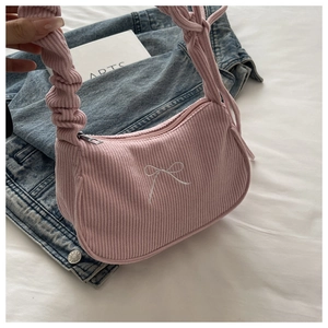 Detailed texture of pink corduroy shoulder bag with bow embroidery and ruched strap