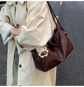 Detail of dark brown tote bag with ROCHAS embossing and leopard Hello Kitty charm